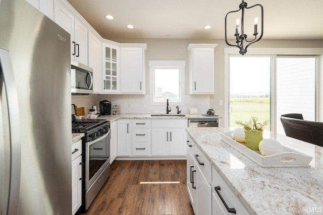 kitchen with white cabinets, stainless steel appliances, a chandelier, sink, and dark wood-type flooring