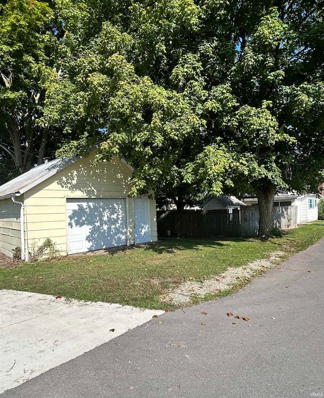 view of property exterior featuring a garage, a yard, and an outbuilding