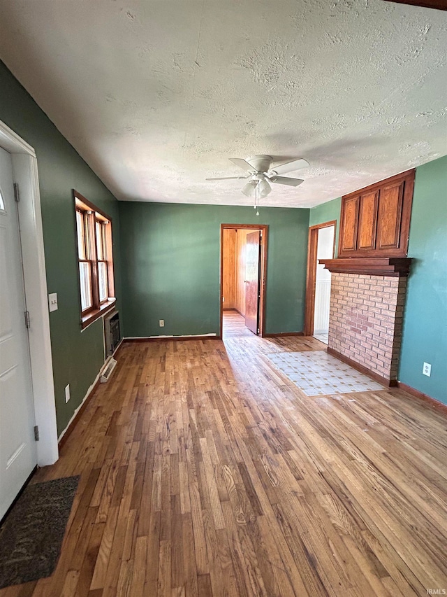 unfurnished living room with hardwood / wood-style floors, ceiling fan, and a textured ceiling