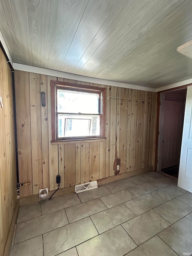 tiled spare room featuring wood walls and wooden ceiling