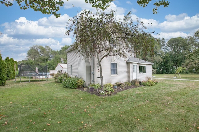 view of side of home featuring a trampoline and a lawn