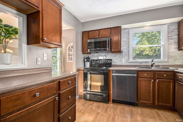 kitchen with backsplash, stainless steel appliances, sink, and light hardwood / wood-style floors