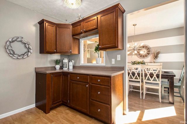 kitchen with light hardwood / wood-style flooring, a notable chandelier, and a textured ceiling