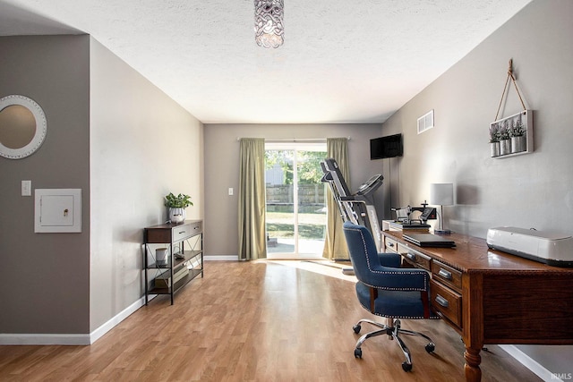 office area with light hardwood / wood-style floors and a textured ceiling