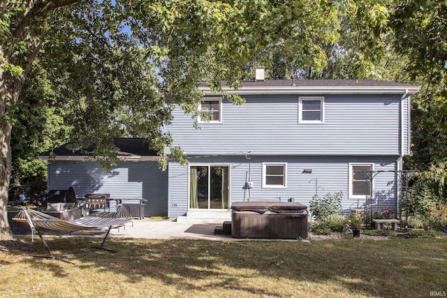 rear view of house with a hot tub, a yard, and a patio