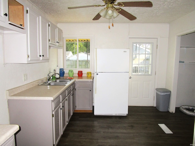 kitchen with a textured ceiling, sink, ceiling fan, and white fridge