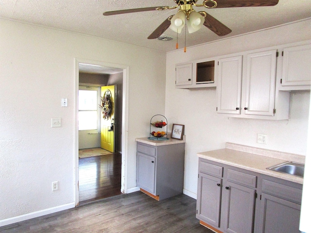 kitchen with a textured ceiling, ceiling fan, sink, and hardwood / wood-style flooring