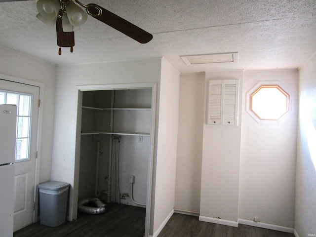 unfurnished bedroom with a textured ceiling, white fridge, a closet, dark wood-type flooring, and ceiling fan