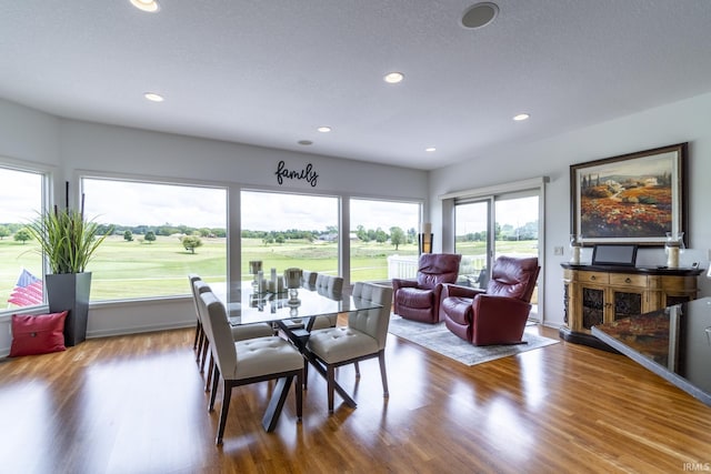 dining space with view of golf course, wood finished floors, and recessed lighting