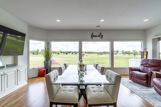 dining space with recessed lighting, view of golf course, and light wood finished floors