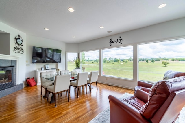 dining room featuring a tiled fireplace and hardwood / wood-style flooring