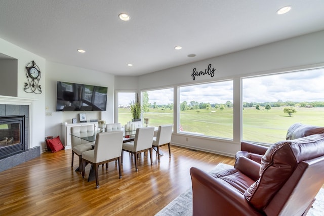 dining space featuring recessed lighting, wood finished floors, and a tiled fireplace