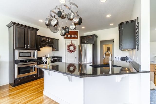 kitchen featuring stainless steel appliances, an inviting chandelier, a sink, a peninsula, and a kitchen bar
