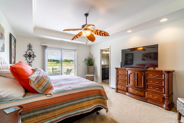 carpeted bedroom featuring crown molding, ensuite bath, a tray ceiling, access to outside, and ceiling fan