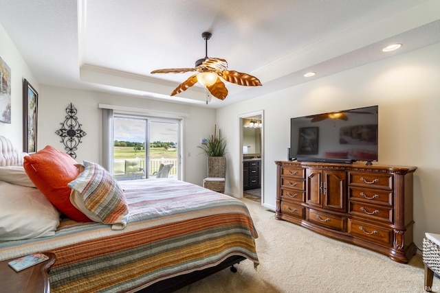 bedroom with a tray ceiling, connected bathroom, access to outside, light colored carpet, and ceiling fan