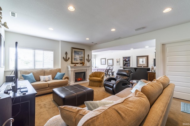 living area featuring light colored carpet, a lit fireplace, visible vents, and recessed lighting