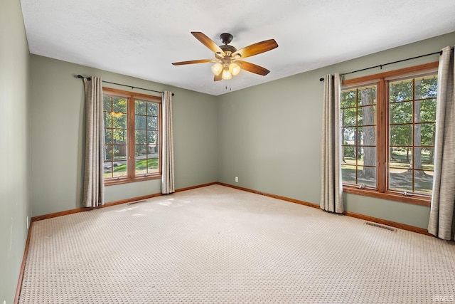 spare room featuring ceiling fan, plenty of natural light, and light carpet