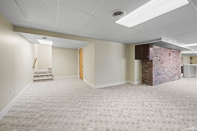 basement featuring a drop ceiling, brick wall, and carpet