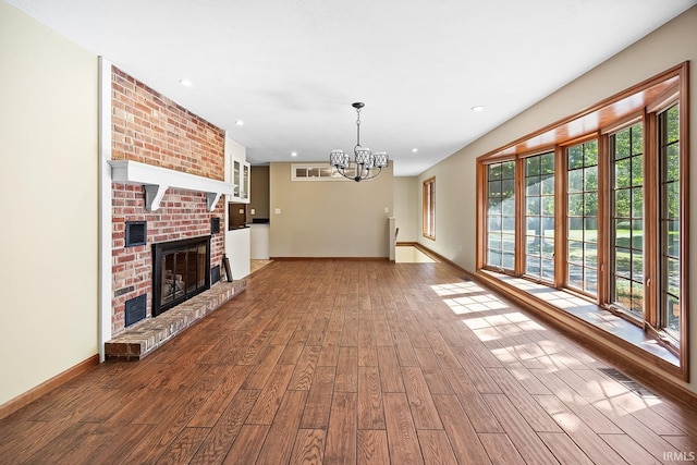 unfurnished living room featuring a fireplace, hardwood / wood-style flooring, and a chandelier