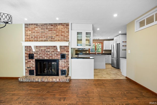 kitchen featuring light wood-type flooring, a fireplace, stainless steel refrigerator, a textured ceiling, and white cabinets