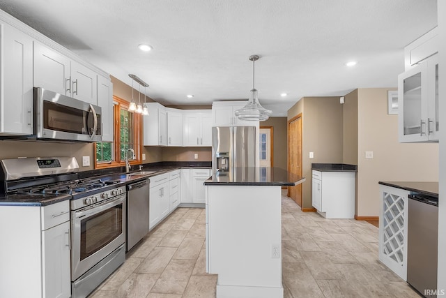 kitchen featuring white cabinets, hanging light fixtures, appliances with stainless steel finishes, sink, and a kitchen island