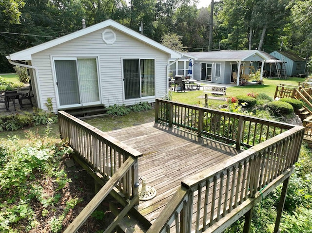 wooden deck with a lawn and a patio