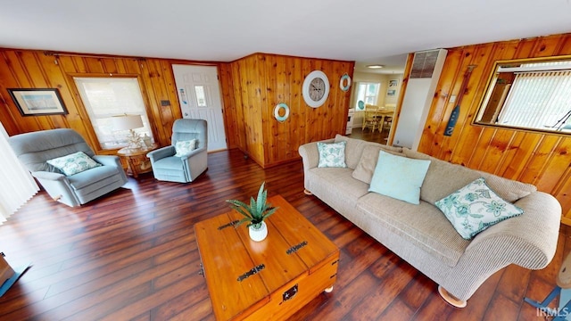 living room featuring dark wood-type flooring, plenty of natural light, and wooden walls