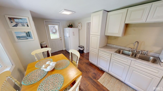 kitchen with white cabinetry, white fridge, sink, and dark hardwood / wood-style flooring