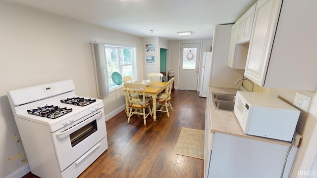 kitchen featuring dark wood-type flooring, sink, white appliances, and white cabinetry