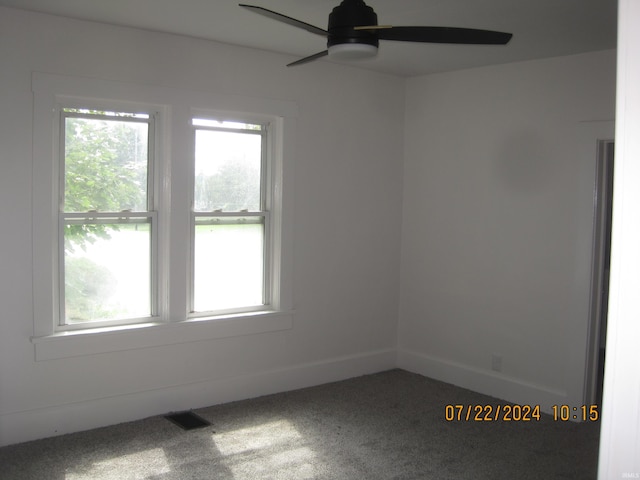 carpeted spare room featuring a wealth of natural light and ceiling fan