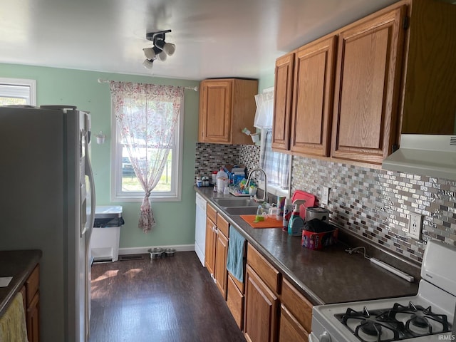 kitchen with white appliances, dark hardwood / wood-style flooring, sink, and tasteful backsplash