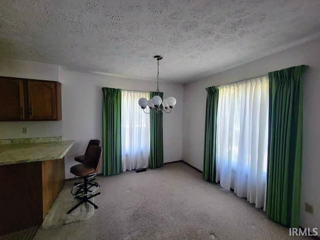 unfurnished dining area featuring a textured ceiling, light carpet, and a chandelier