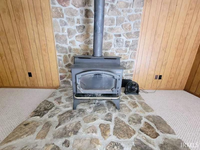 interior details featuring carpet, a wood stove, and wooden walls