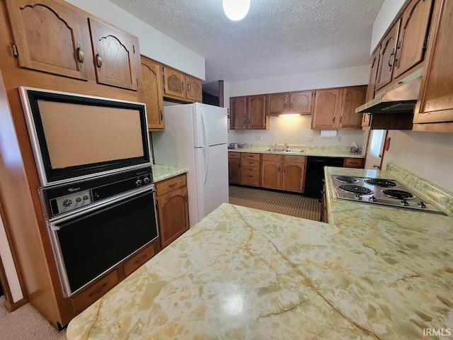 kitchen with carpet flooring, sink, black appliances, and a textured ceiling