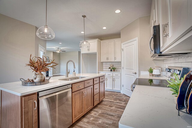 kitchen featuring white cabinets, appliances with stainless steel finishes, sink, dark hardwood / wood-style floors, and a kitchen island with sink