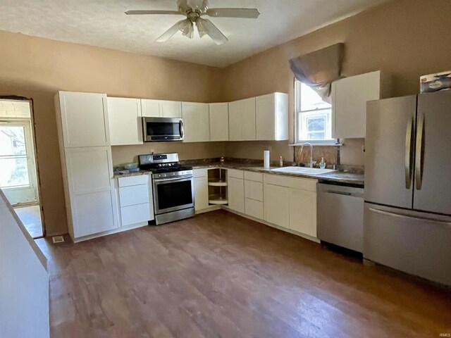 kitchen with sink, ceiling fan, appliances with stainless steel finishes, hardwood / wood-style flooring, and white cabinets