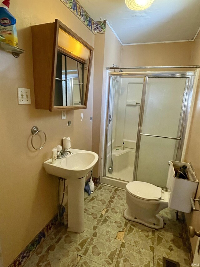 bathroom featuring an enclosed shower, toilet, and ornamental molding