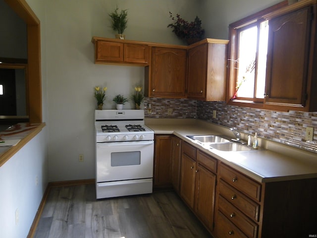 kitchen featuring backsplash, gas range gas stove, sink, and dark wood-type flooring