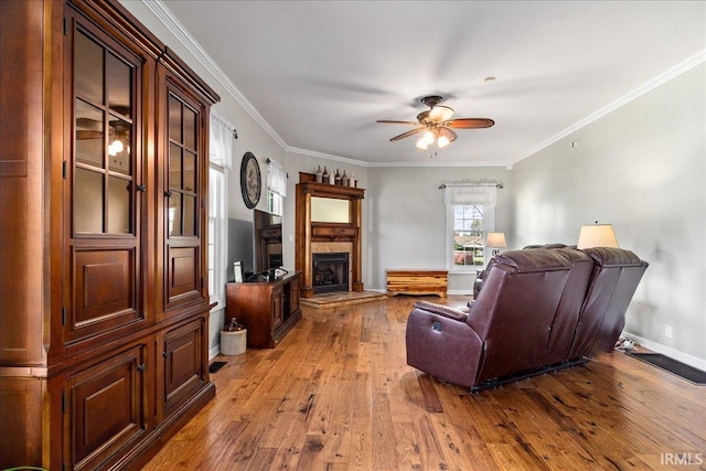 living room featuring hardwood / wood-style floors, ceiling fan, and crown molding