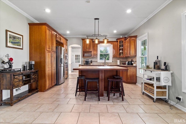 kitchen featuring ornamental molding, a kitchen island, a breakfast bar, and stainless steel refrigerator with ice dispenser