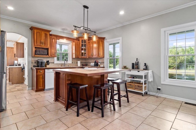 kitchen with pendant lighting, a kitchen island, a wealth of natural light, and tasteful backsplash