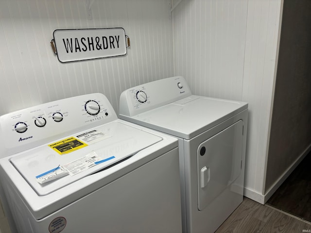 clothes washing area with wooden walls, dark hardwood / wood-style flooring, and separate washer and dryer