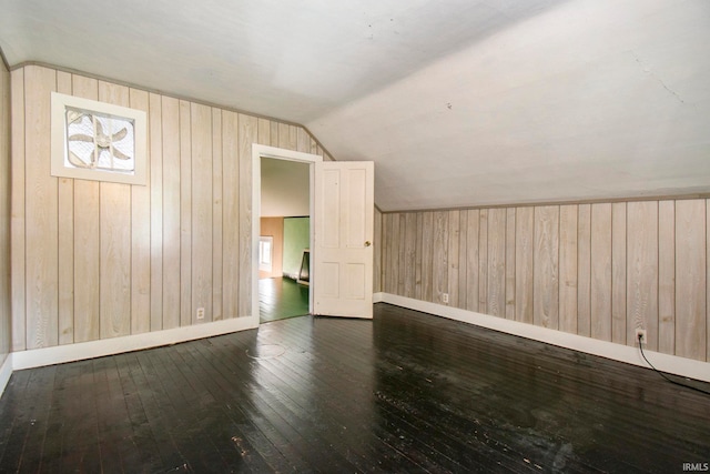 bonus room with dark wood-type flooring, vaulted ceiling, and wood walls