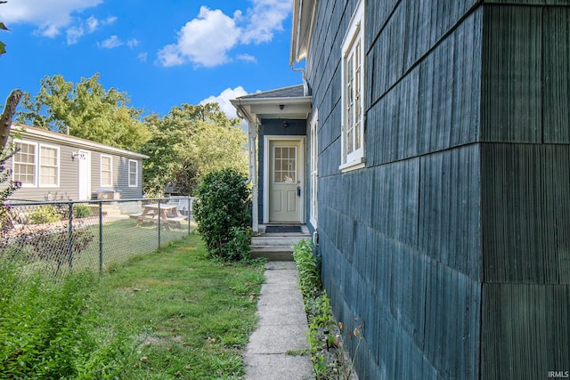 view of exterior entry featuring a lawn