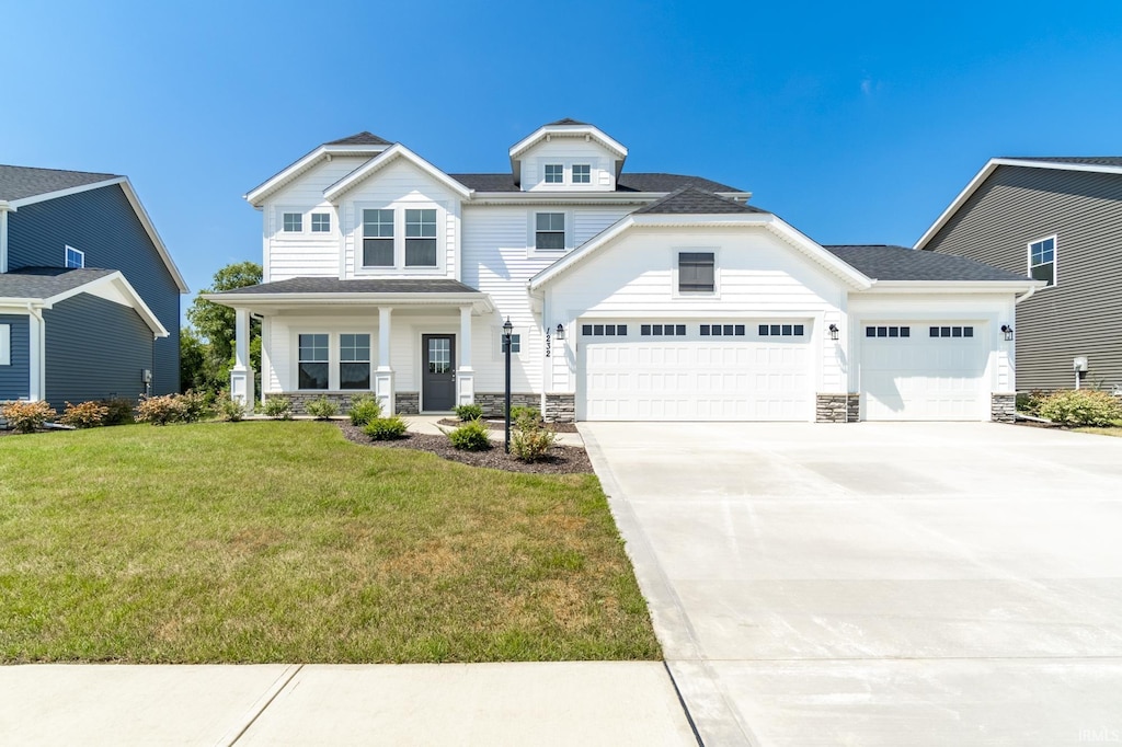 view of front facade featuring concrete driveway, an attached garage, stone siding, a front yard, and covered porch