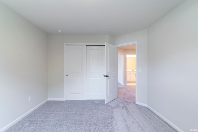 unfurnished bedroom with a closet and light colored carpet