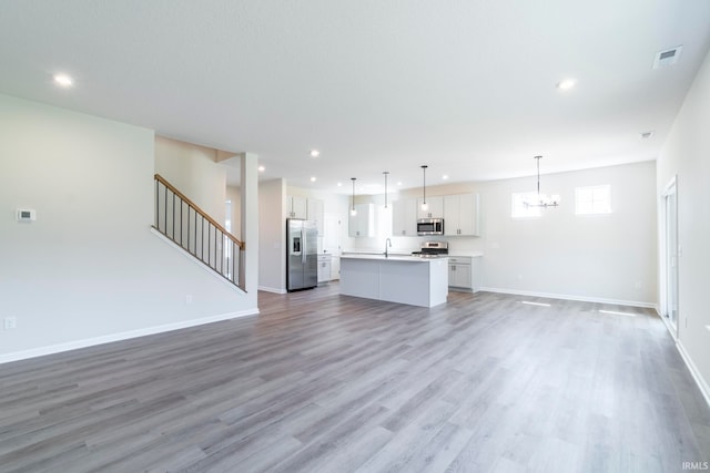 unfurnished living room featuring light hardwood / wood-style flooring, sink, and a chandelier