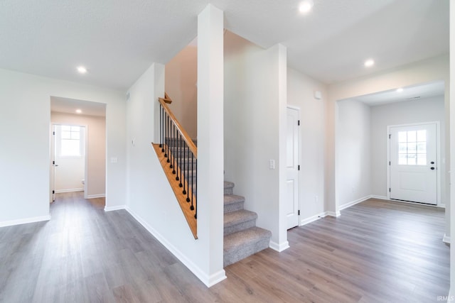 staircase with a textured ceiling, plenty of natural light, and wood-type flooring