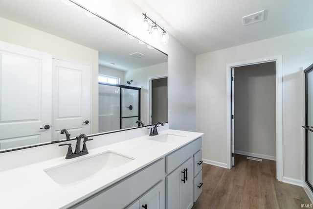 bathroom featuring vanity, a textured ceiling, hardwood / wood-style flooring, and a shower with shower door