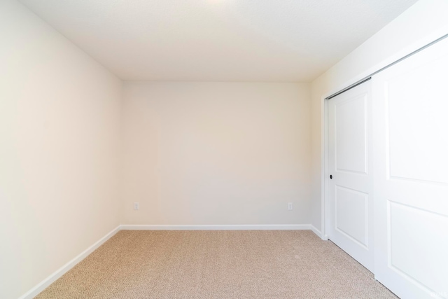 unfurnished bedroom featuring light colored carpet and a closet